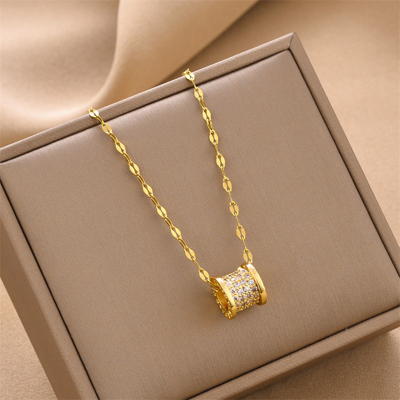 Gold cylindrical pendant necklace with sparkling cylinder charm and link chain in box.