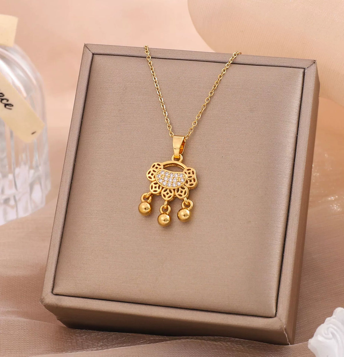 Gold-tone coin lock charm necklace with floral filigree pendant and dangling beads