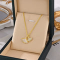 Gold double ginkgo leaf charm necklace with clear stones, on beige jewelry display