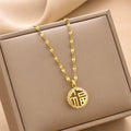 Gold round charm necklace with textured chain, sparkling letter-style charm in box.