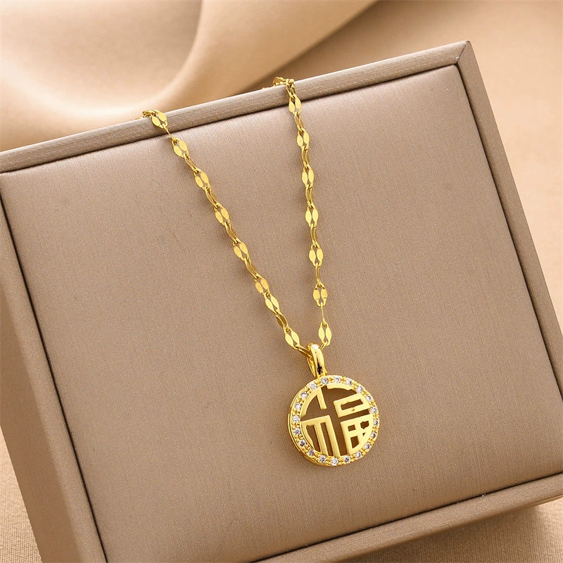 Gold round charm necklace with textured chain, sparkling letter-style charm in box.