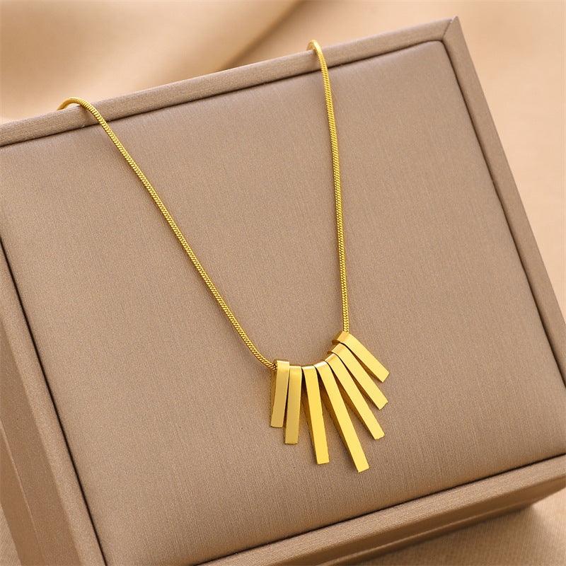 Gold-tone fringe charm necklace with pendant detail on a slim chain