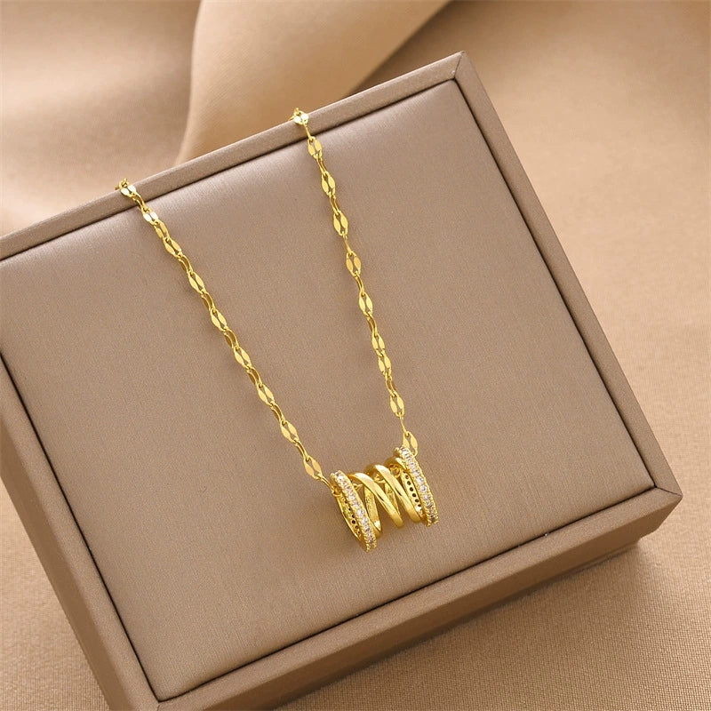 Gold-tone coil pendant necklace with faceted charm on link chain, displayed in box