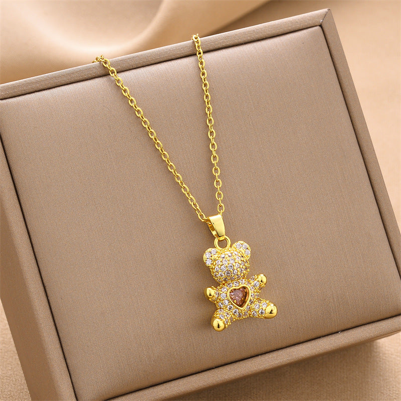 Gold-tone mini bear charm necklace with heart-shaped gem pendant on chain