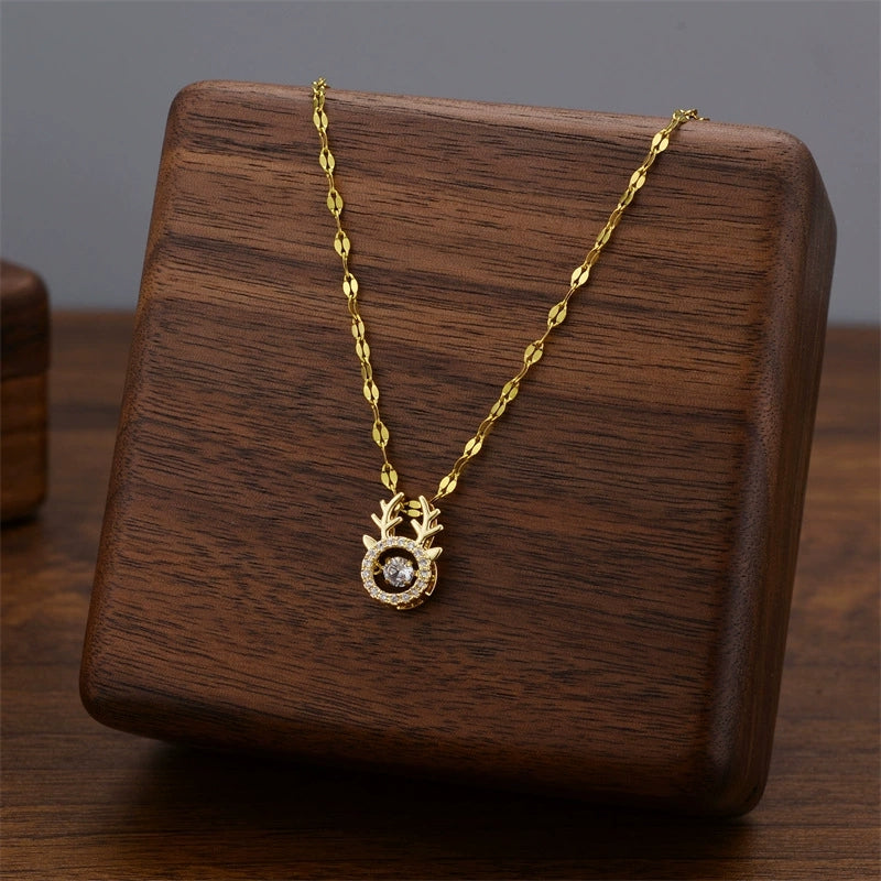 Gold-tone branch charm necklace with circular crystal pendant on a wooden stand