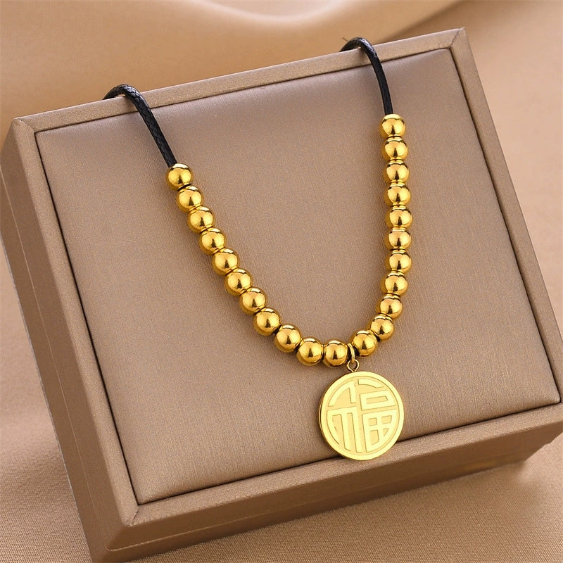 Gold beaded pendant necklace with black cord and round disc charm