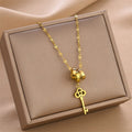 Gold key charm necklace with triple-ring clasp and clover key pendant