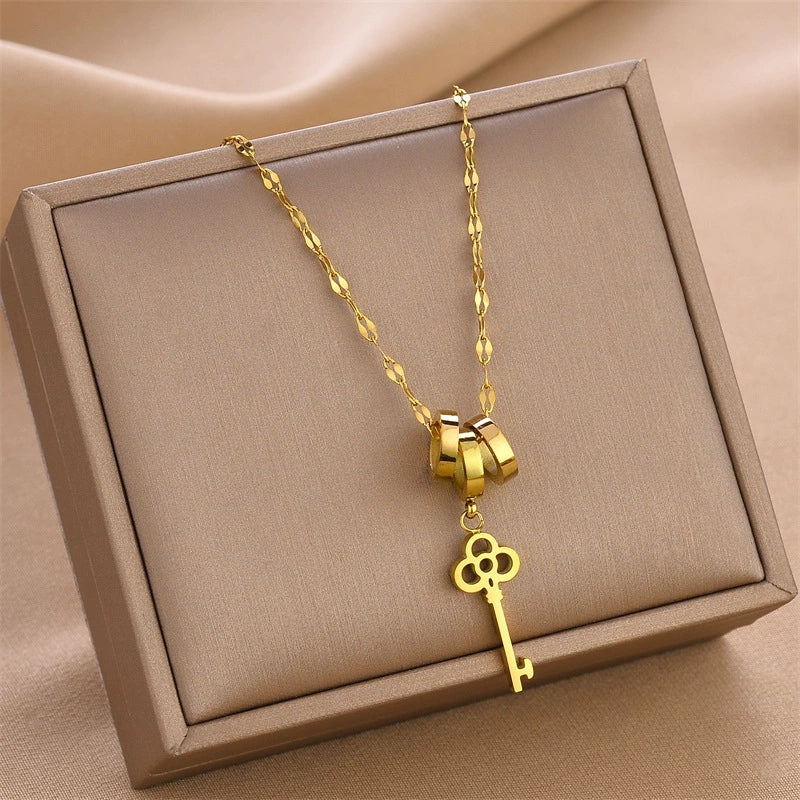 Gold key charm necklace with triple-ring clasp and clover key pendant