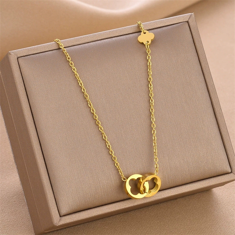 Gold-tone clover pendant necklace with slim chain, displayed in a box