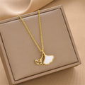 Gold-tone ginkgo leaf pendant necklace with white enamel leaf and small gem accents