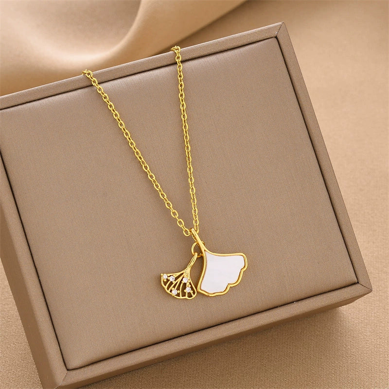 Gold-tone ginkgo leaf pendant necklace with white enamel leaf and small gem accents