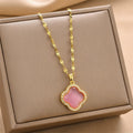 Gold-tone chain necklace with pink quatrefoil pendant framed by clear rhinestones