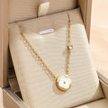 Gold-tone flower petal pendant necklace with round white inlay and dangling chain