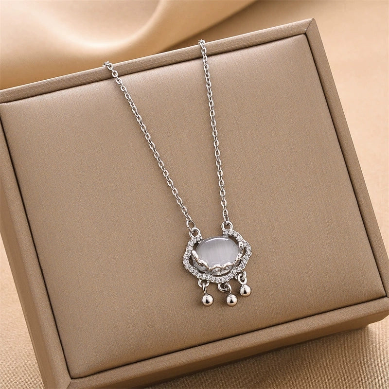 Silver lock charm necklace with oval pendant, rhinestone frame, and three bead accents