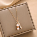Gold-tone peanut charm necklace with two pearl drops, dangle detail