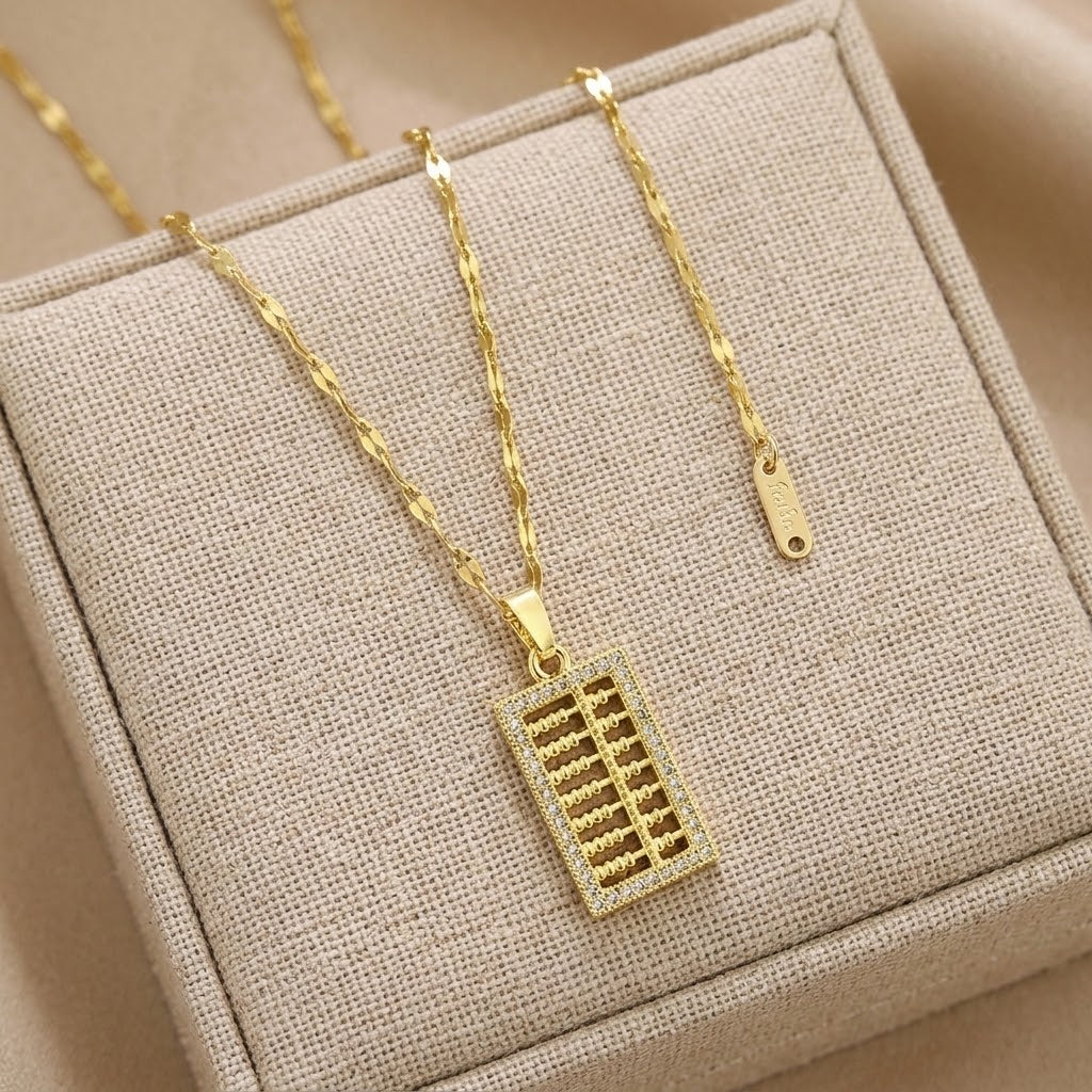 Gold-tone necklace featuring a mini abacus charm pendant and chain links