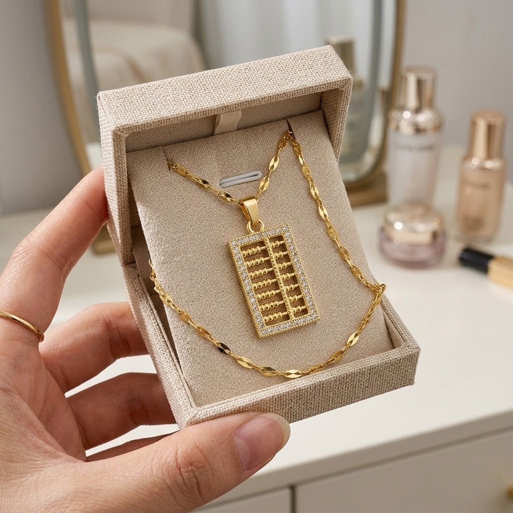 Gold-tone mini abacus charm necklace shown in a square jewelry box