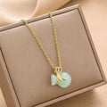 Gold-tone chain charm necklace with mint green fortune bag and bow detail