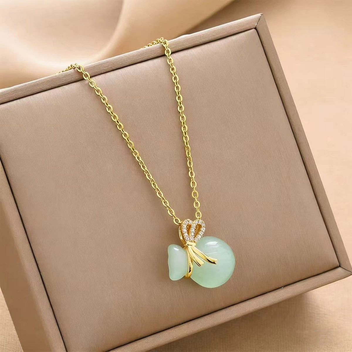 Gold-tone chain charm necklace with mint green fortune bag and bow detail