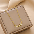 Gold-tone charm necklace with fishbone pendant set with rhinestone accents