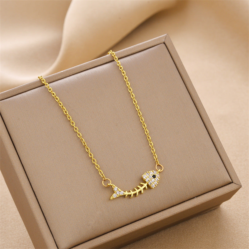 Gold-tone charm necklace with fishbone pendant set with rhinestone accents