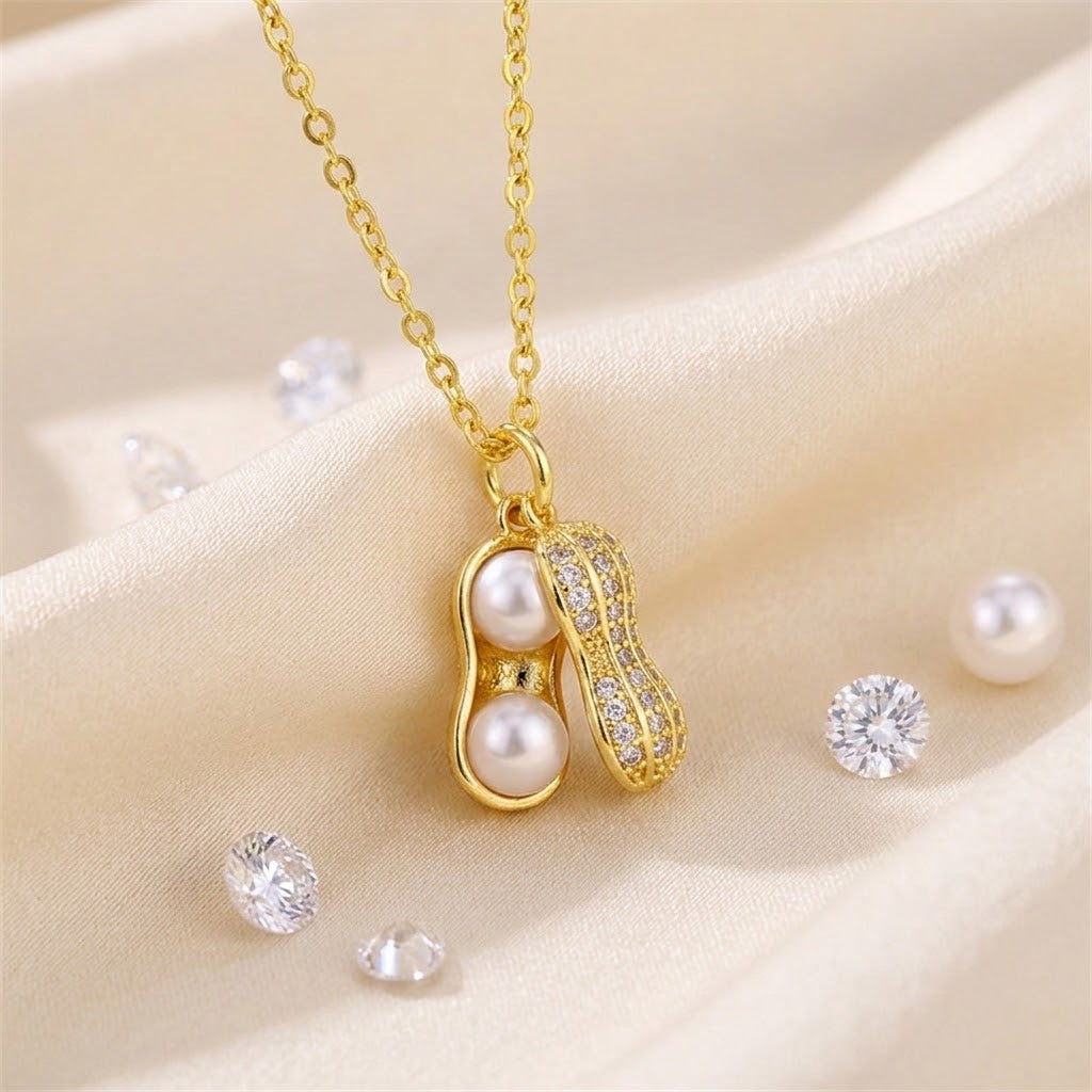 Gold-tone peanut-shaped charm necklace with white pearl beads and crystal accents