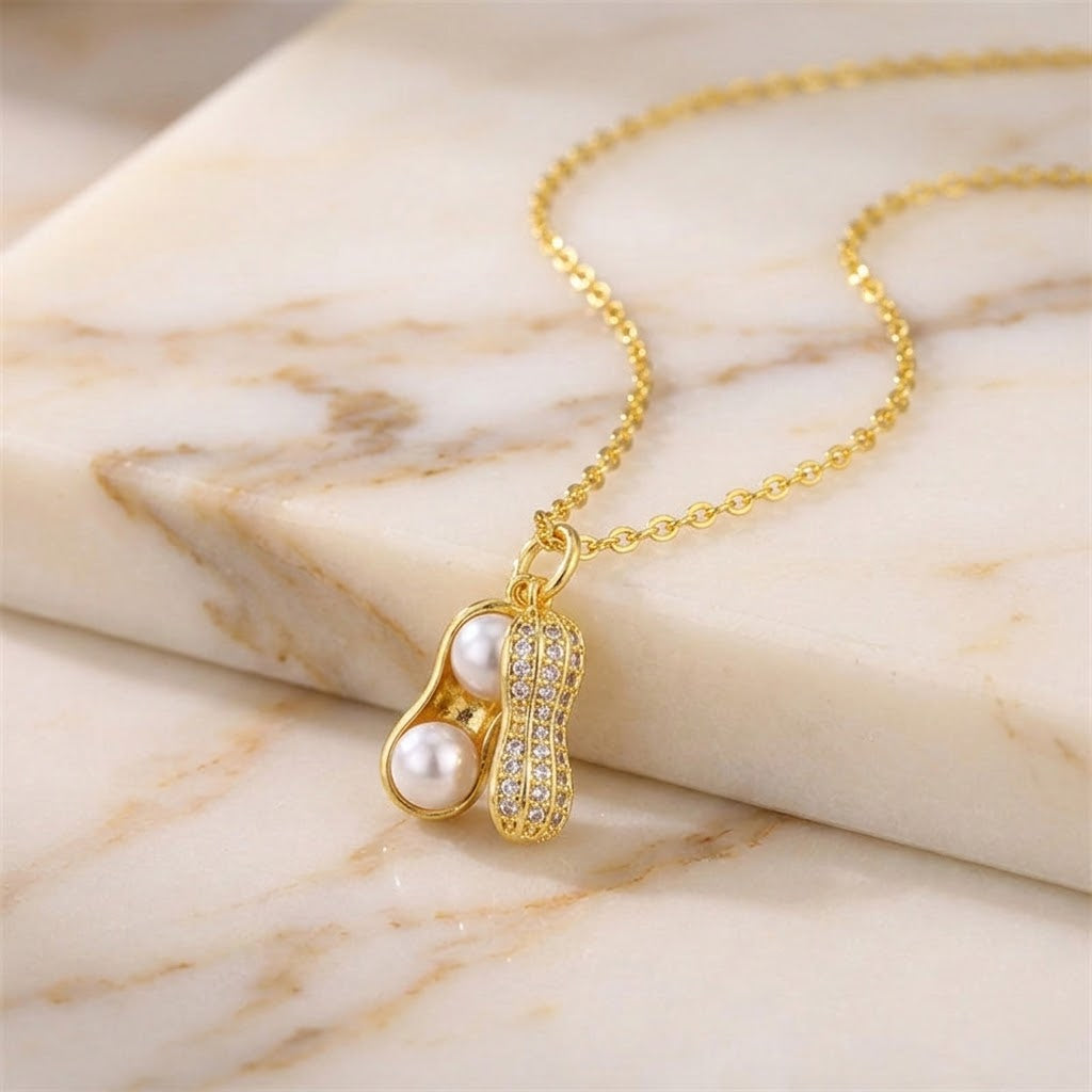 Gold-tone peanut-shaped pearl charm necklace with crystal pave and white pearl detail