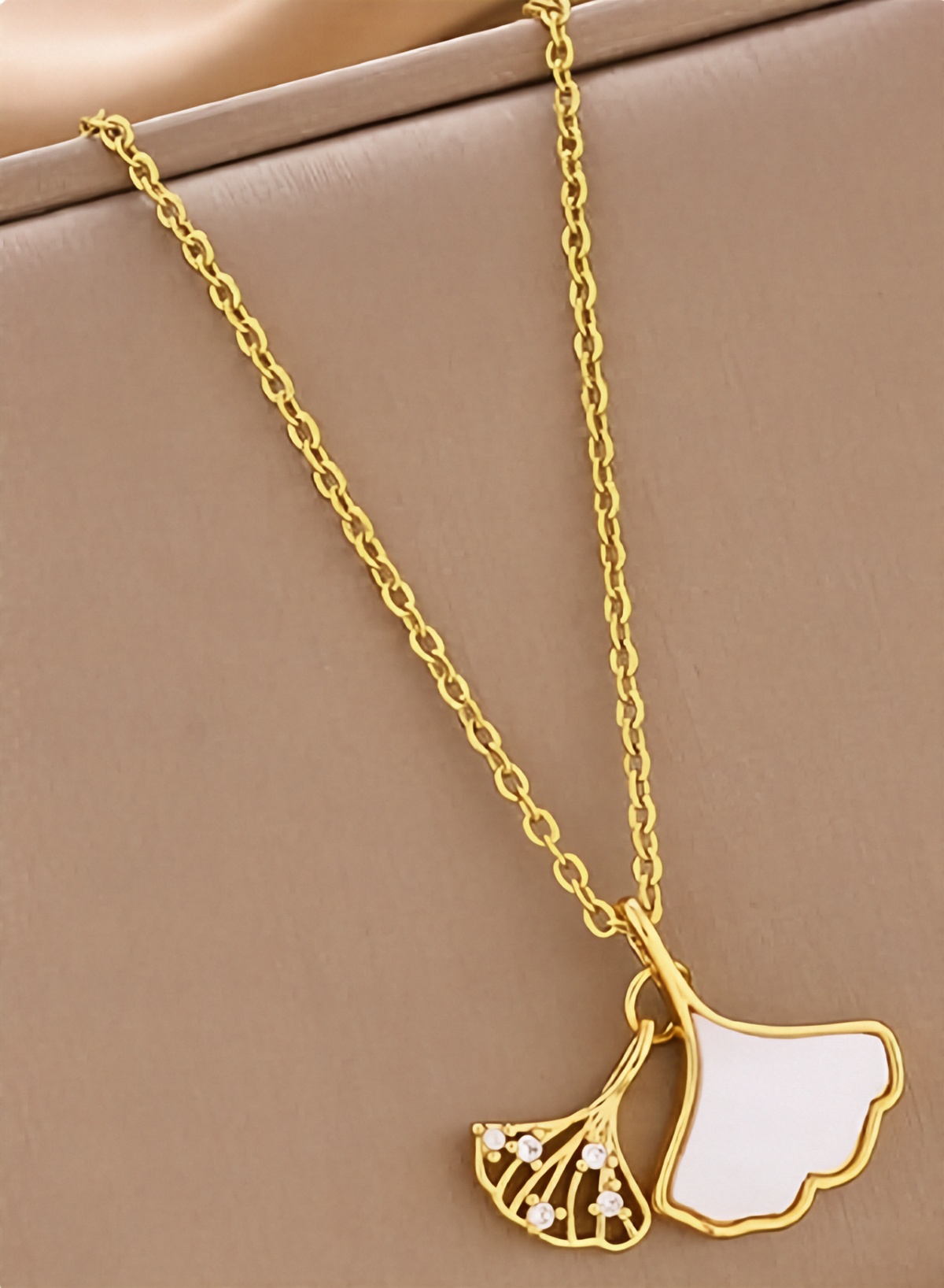 Gold-tone ginkgo leaf pendant necklace with dangling white enamel leaf and filigree charm