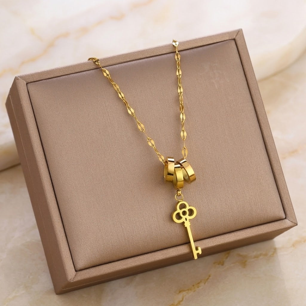 Gold key charm necklace with triple-ring clasp and clover key pendant, long chain