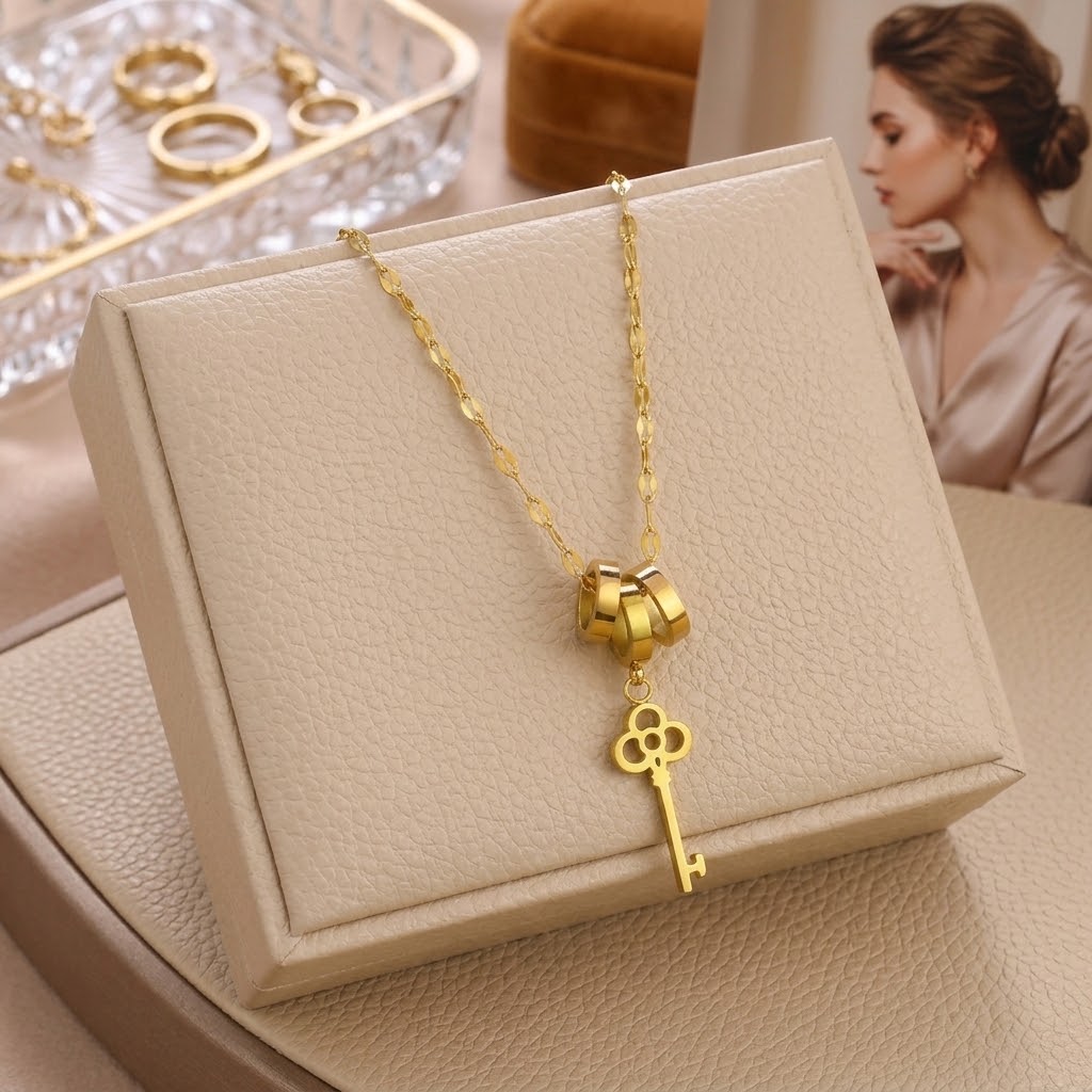 Gold key charm necklace with triple-ring clasp and clover key pendant