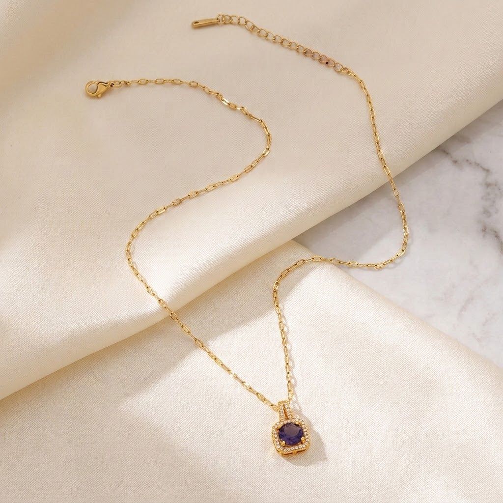 Gold pendant necklace with dark-blue cushion gemstone on halo setting