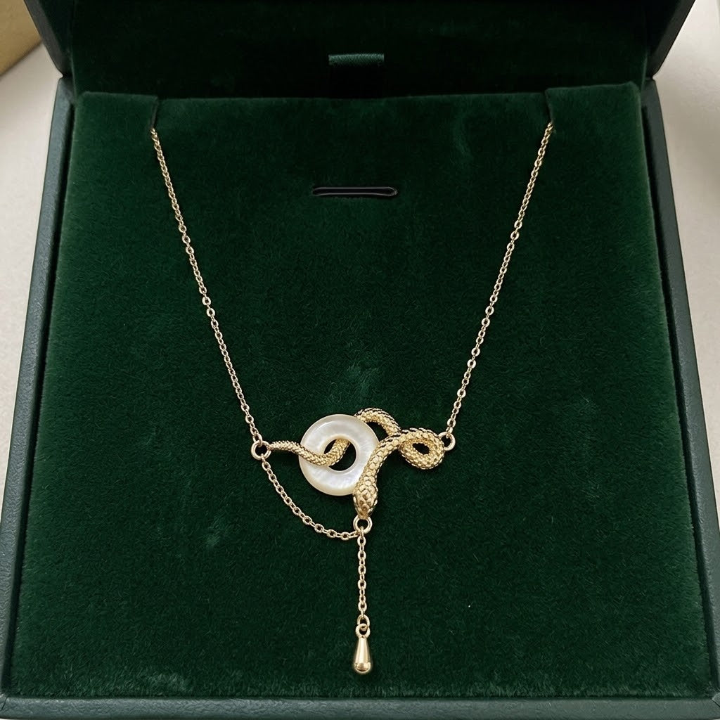 Gold-tone snake through-ring pendant necklace with white oval ring and dangling teardrop