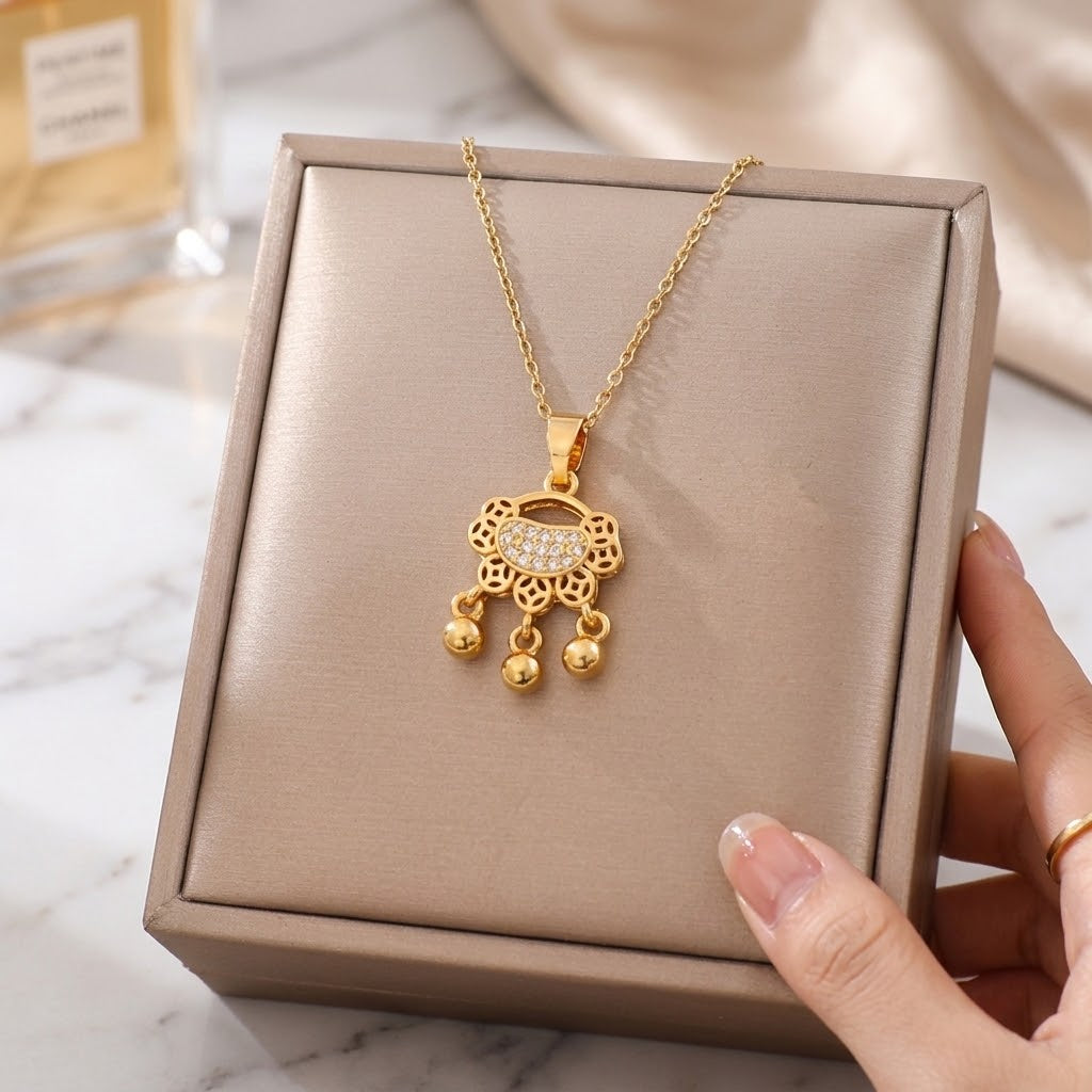 Gold-tone charm necklace with coin lock pendant and three dangling bead drops