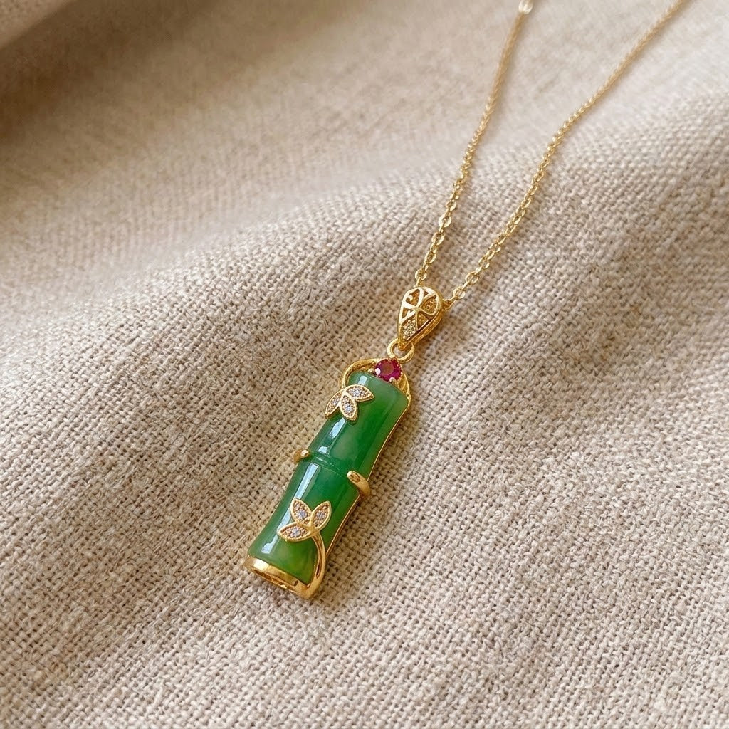 Gold necklace with green segmented pendant, heart-shaped stones, and link chain