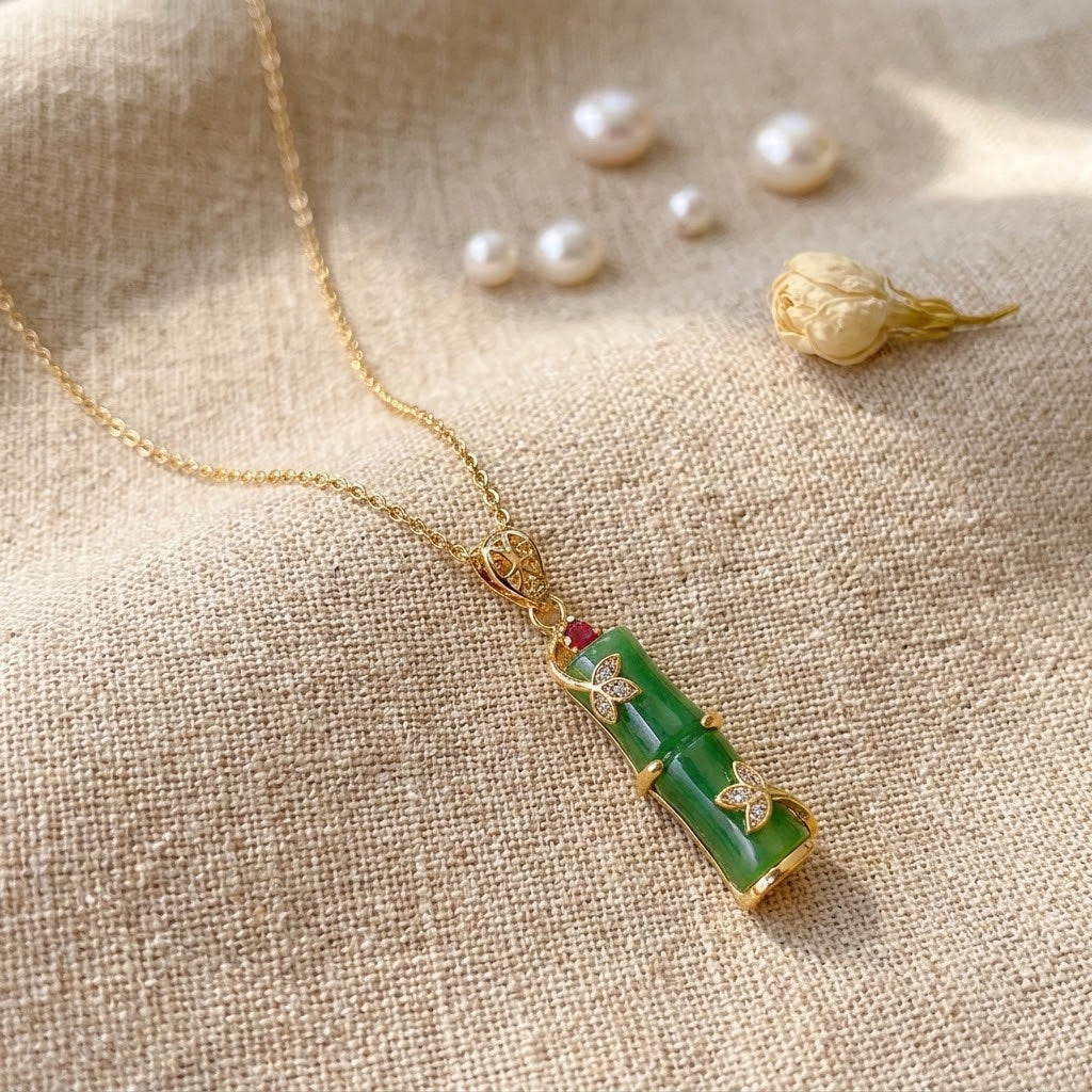Gold necklace with green segmented pendant featuring red and heart-shaped crystal accents