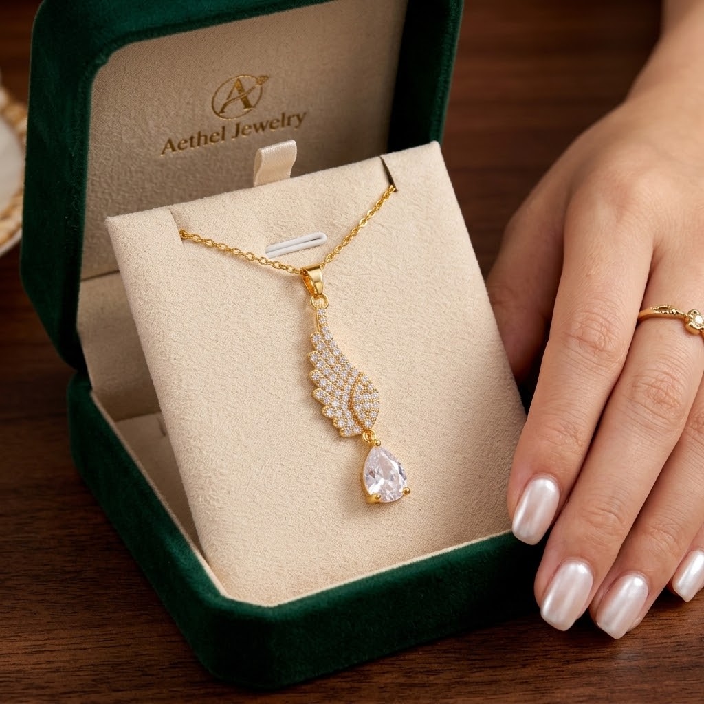 Gold-tone wing teardrop charm necklace with pavé stones and clear drop pendant