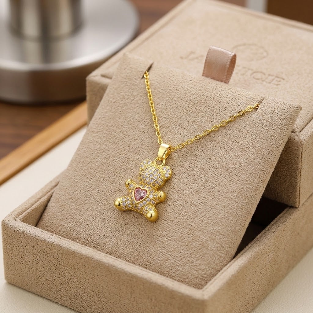 Gold-tone mini bear charm necklace with heart-shaped gem pendant in box