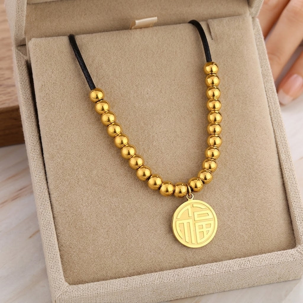 Gold beaded pendant necklace with black cord and round disc medallion