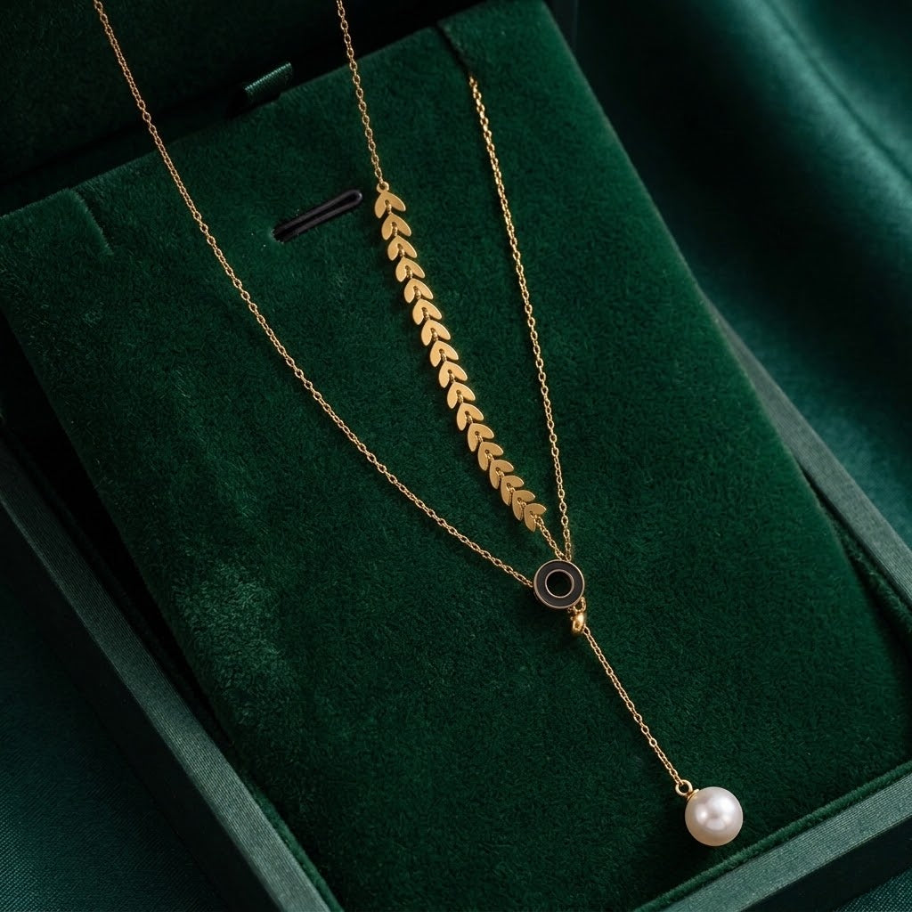 Gold chain necklace with leaf cluster charm, round ring accent, and pearl bead