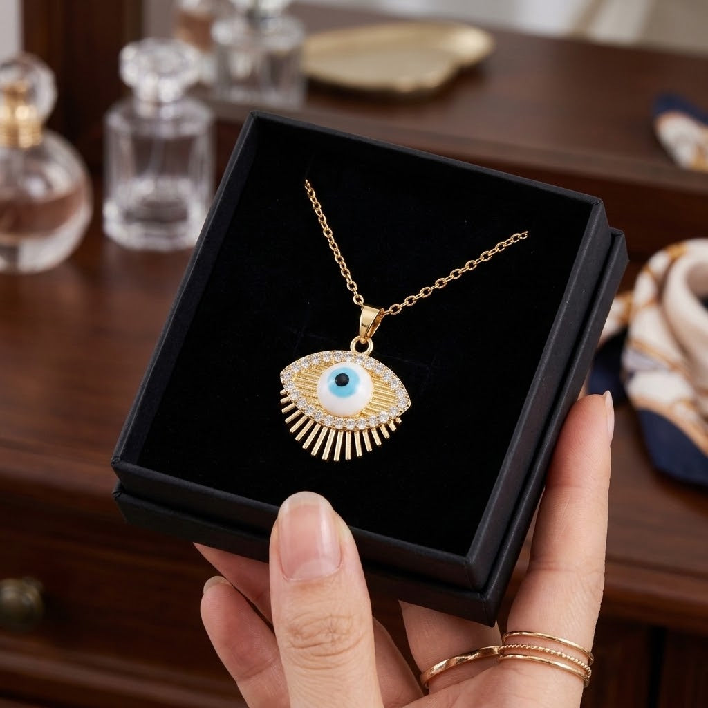 Gold eye charm necklace with blue eye pendant and fan-detail charm in black box