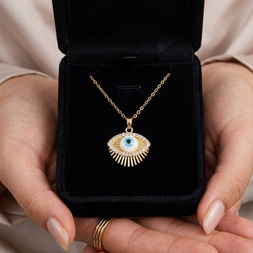Gold eye charm pendant necklace with blue eye centerpiece in open black jewelry box