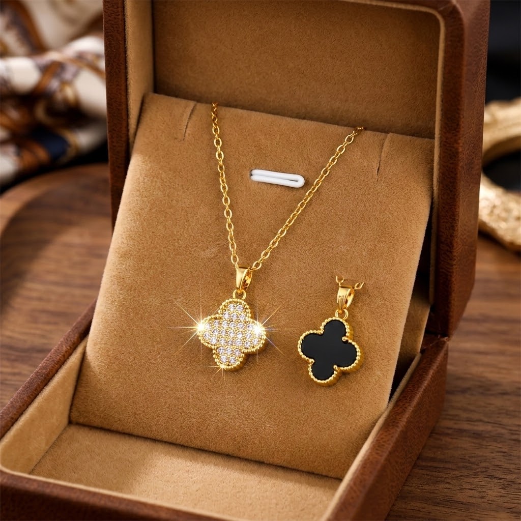 Gold floral pendant necklace with black clover charm beside it