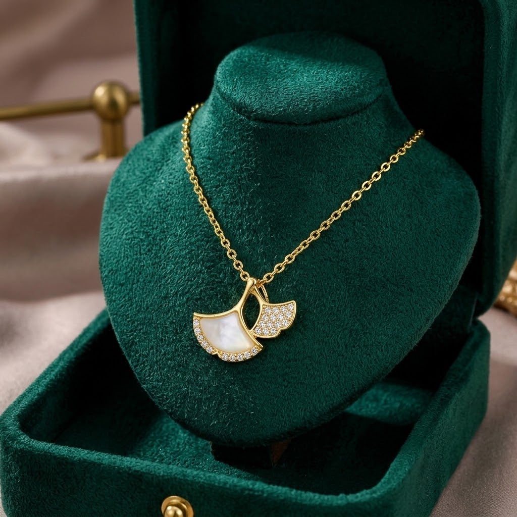 Gold double ginkgo leaf charm necklace with clear stones, on green velvet display