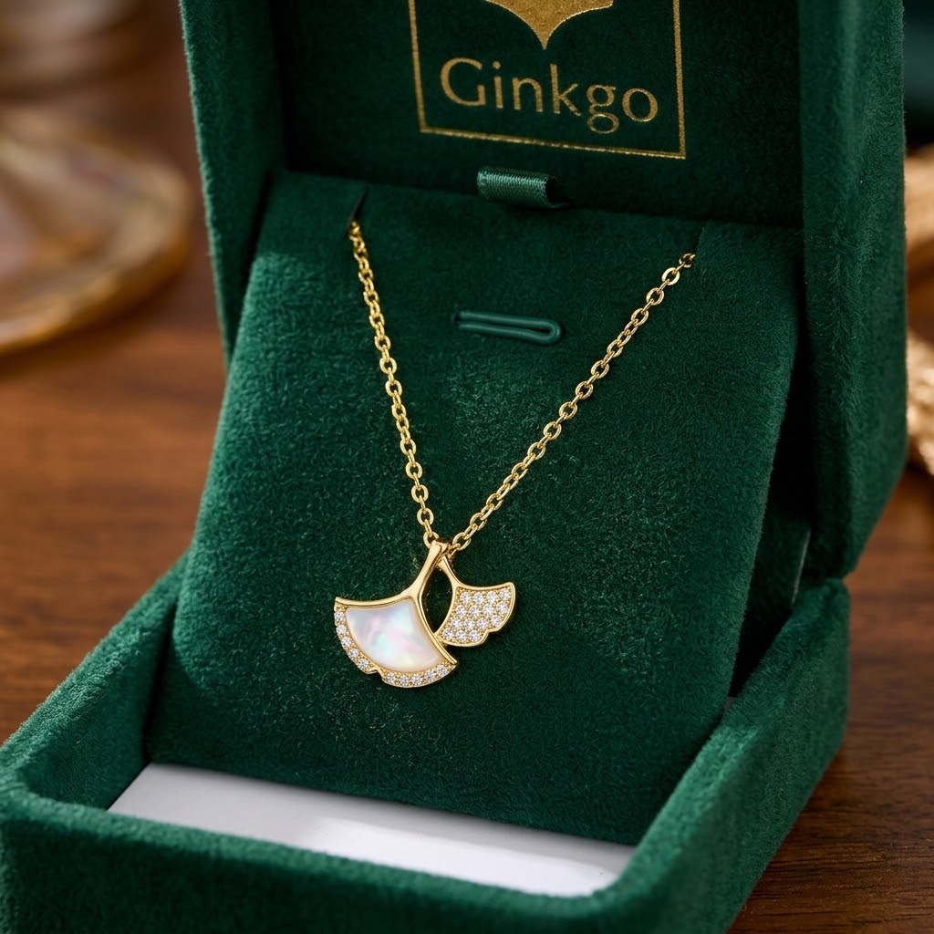 Gold double ginkgo leaf charm necklace with clear stones on green velvet display