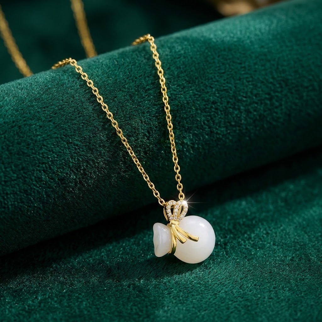 Gold-tone necklace with crown charm and white bead pendant with bow and ring accents