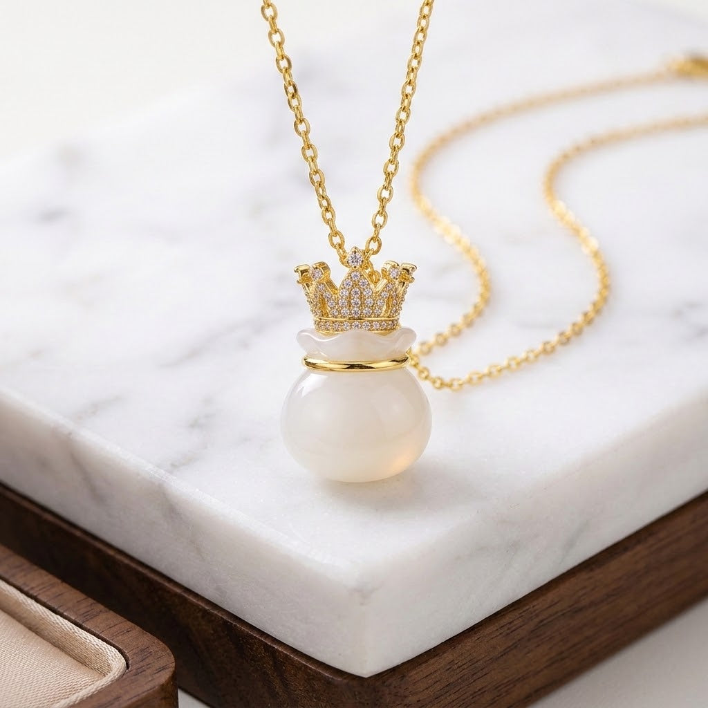 Gold-tone necklace with crown top and white bead pendant, centered on short chain