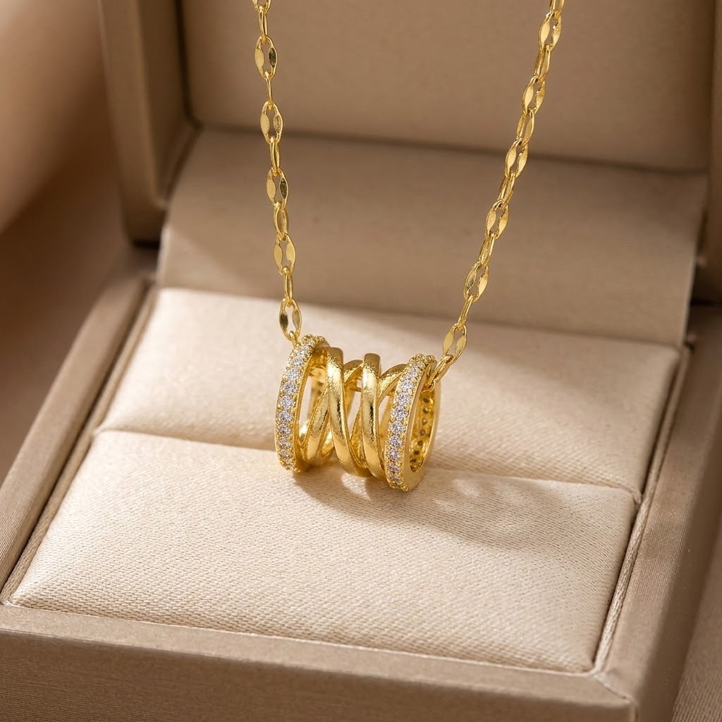Gold-tone coil pendant necklace with three-ring charm and clear stones on link chain