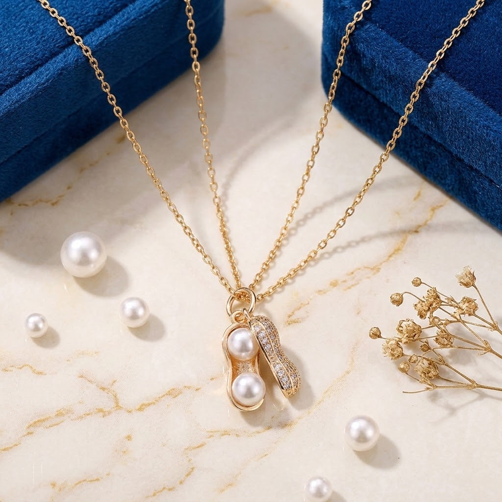 Gold-tone peanut-shaped charm necklace with white pearl beads and crystal detailing