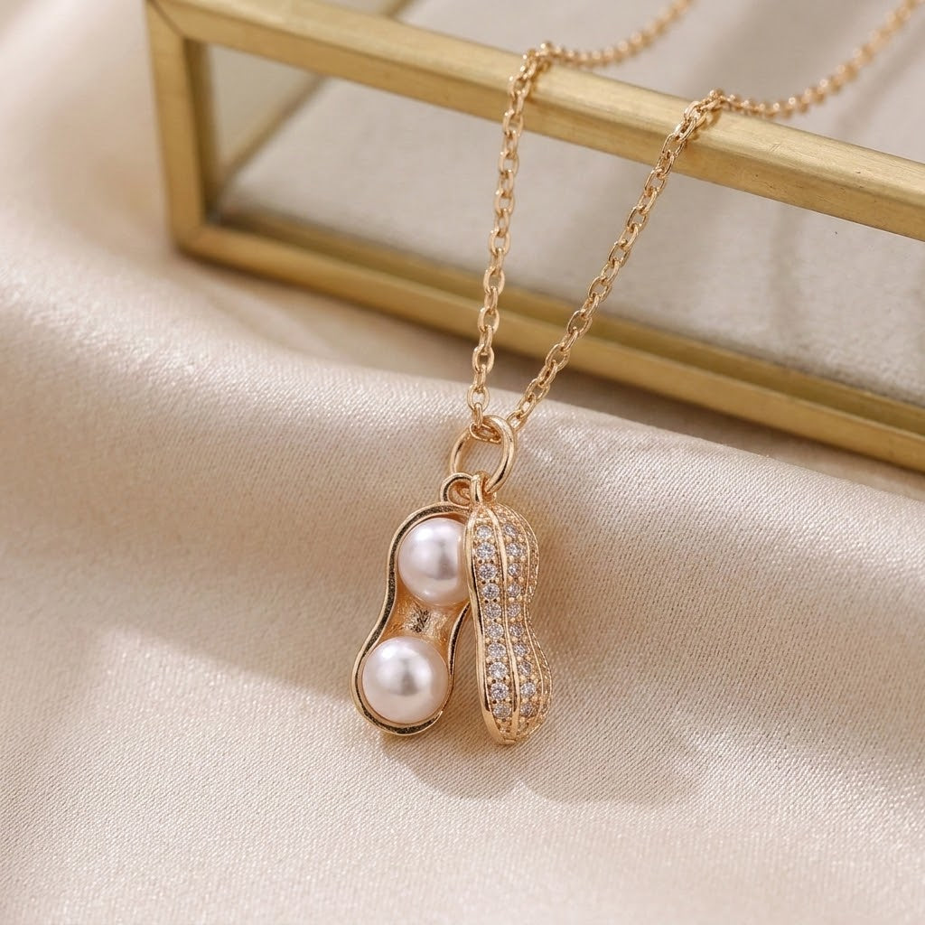 Gold-tone peanut-shaped charm necklace with white pearl beads and CZ-like crystal pave