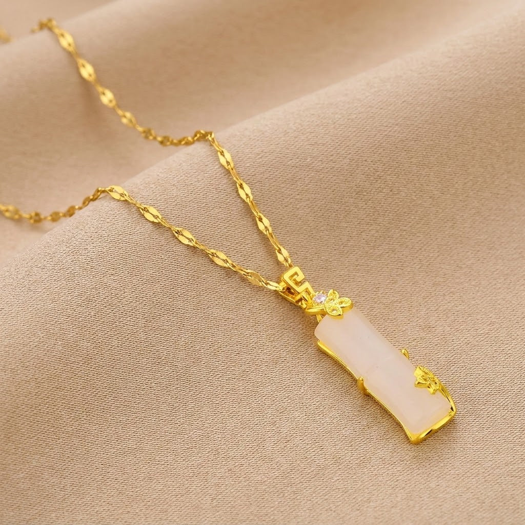 Gold necklace with pale pink segmented pendant and ornate openwork heart details